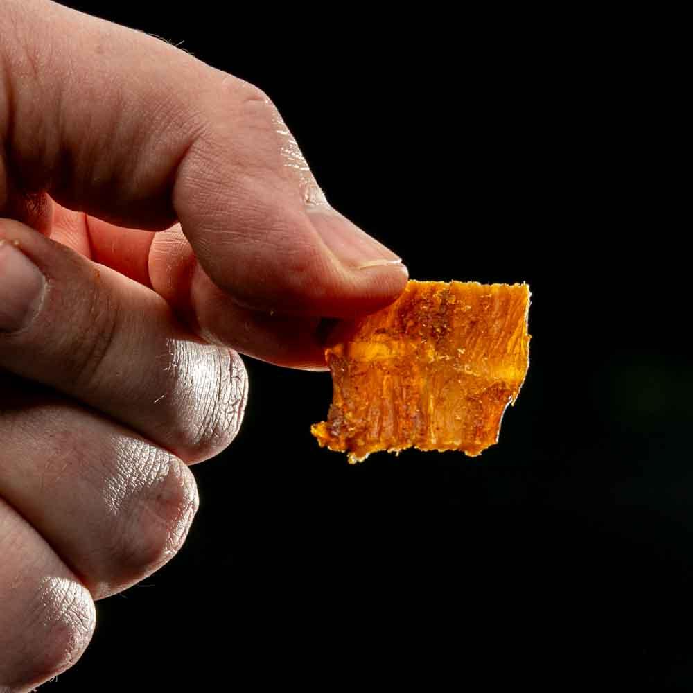 Hand houdt stukje chicken jerky vast