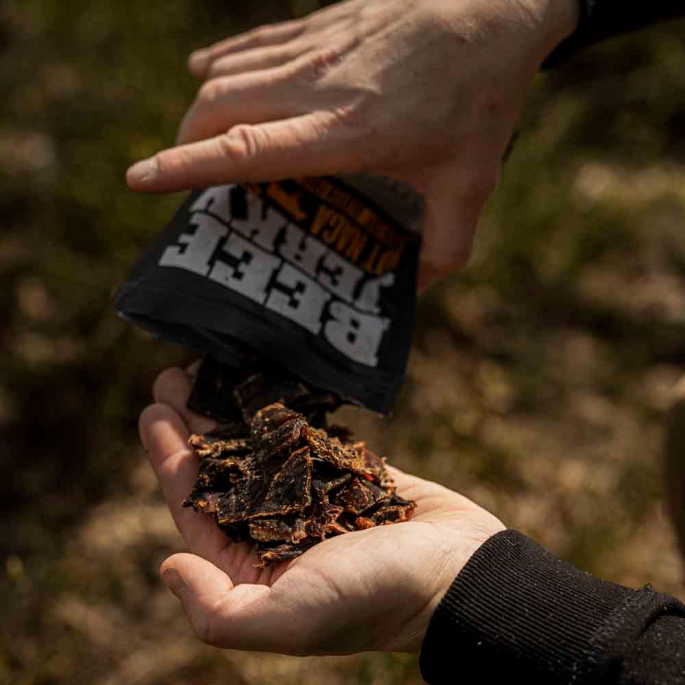 Hand met stukjes gedroogd vlees uit box