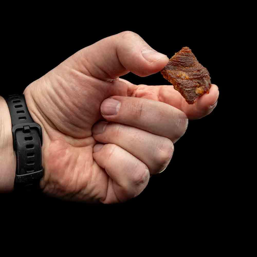 Hand houdt stukje Korean pork jerky vast